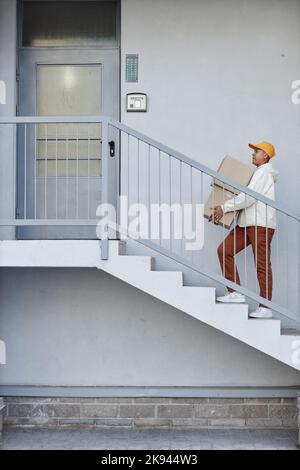 Die Grafik ist eine minimale Aufnahme des Lieferers, der die Treppe zur Haustüre hinaufgeht Stockfoto
