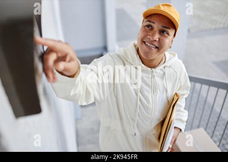 Porträt einer lächelnden Frau mit Paketen und klingelnder Türklingel Stockfoto