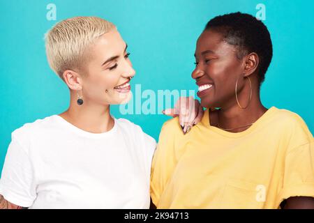 Manchmal kennst du mich besser als ich selbst. Studioaufnahme von zwei glücklichen jungen Frauen, die vor türkisfarbenem Hintergrund posieren. Stockfoto