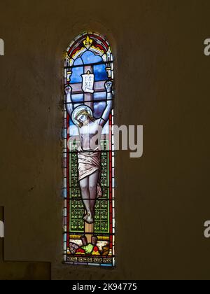 Buntglasfenster in der St. Aidans Church, Throckrington, Northumberland, Großbritannien, die Christus am Kreuz zeigt. Stockfoto