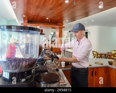 Haikou, Chinas Provinz Hainan. 18. Oktober 2022. Sebastian Hahn aus Berlin, Deutschland, macht Kaffee in seinem Café in Haikou, südchinesische Provinz Hainan, 18. Oktober 2022. Sebastian Hahn mischte Biersirup, Milch und Espresso und machte geschickt eine Tasse Bier Latte, ein Spezialgetränk aus seinem Café. „Das schmeckt ganz besonders und mir persönlich gefällt es sehr gut“, sagte er. MIT 'Across China: German man suks New career and love in Hainan' Credit: Zhou Huimin/Xinhua/Alamy Live News Stockfoto