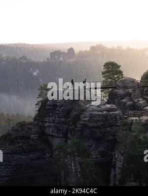 Eine szenische Aufnahme der Menschen, die während des Sonnenuntergangs die Treppen auf hohen Bastei-Felsformationen in Deutschland gehen Stockfoto