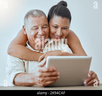 Tablet, Internet und Liebe mit einem älteren Paar, das online mit Wireless-Technologie im Haus zusammen surfen. Beziehung, Lächeln und glücklich mit einem Stockfoto