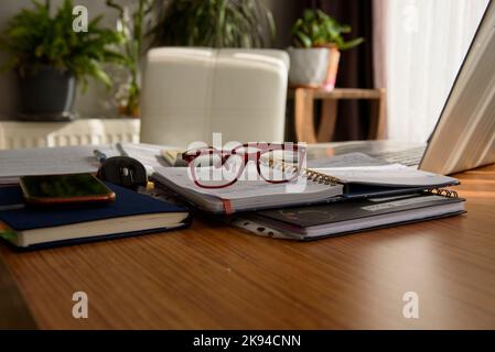 Brille und Notizen auf dem Schreibtisch am Arbeitsplatz zu Hause Stockfoto