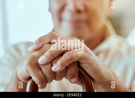 Älterer Mann, Hände und Stock für Behinderung, Arthritis oder Osteoporose zu Hause. Nahaufnahme, Ruhestand und behinderte ältere Männer mit Holzlaufen Stockfoto