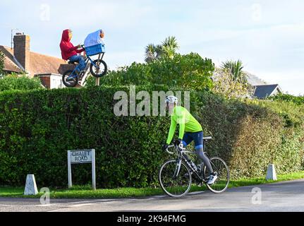 Worthing UK 26. October 2022 - Ein Radfahrer kommt an der Vogelscheuche ET vorbei, die beim jährlichen Vogelscheuche-Festival im Dorf Ferring in der Nähe von Worthing, West Sussex, über eine Hecke geflogen ist. Über 70 Vogelscheuchen werden voraussichtlich über die Woche im ganzen Dorf erscheinen : Credit Simon Dack / Alamy Live News Stockfoto