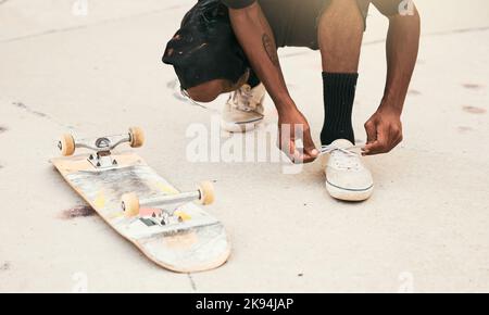 Skater, Schuhe und Schnürsenkel mit Skateboard im Park für Sicherheit, Bewegung und Skaten im Freien in der Stadt. Mann, Turnschuhe und Schnürsenkel auf Füßen, Boden und Stockfoto