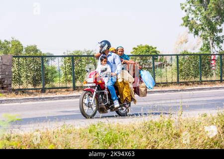 RAJASTHAN, INDIEN - 18. OKTOBER: Mutter, Vater und kleines Kind reiten am 18. Oktober 2012 in Rajasthan, Indien, auf einem Roller durch eine verkehrsreiche Straße auf der Autobahn. U Stockfoto