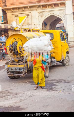 JODHPUR, INDIEN - OCT 23: Indische Frau trägt am 23. Oktober 2012 in Jodhpur, Indien, schwere Last auf ihrem Kopf. Indische Frauen arbeiten mehr als Männer, aber ihre Arbeit Stockfoto