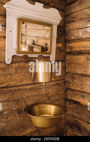 Vintage-Aufnahme eines alten Metallwaschbeckens und Spiegels in einem Holzhaus im Dorf Stockfoto