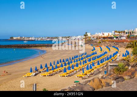 PLAYA BLANCA, SPANIEN - MÄRZ 29: Strand und Geschäfte im Hintergrund an der Strandpromenade. Lanzarote ist ein bevorzugtes Winterziel für Europäer Stockfoto