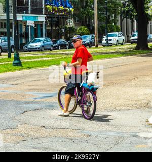 NEW ORLEANS, USA - 15. JULI: Der Mann mit seinem Hund fährt am 15. Juli 2013 in New Orleans, USA, auf dem Fahrrad entlang der Straße. Die Saint Charles Avenue ist breit und Stockfoto