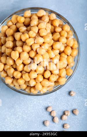 Gekochte Kichererbsen in einer Glasschüssel auf grauem Hintergrund. Stockfoto