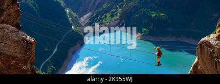 Seilbrücke zwischen zwei Felsen über dem Gittaz-Stausee, Via Ferrata du Roc du Vent, Frankreich, Savoie, Beaufortain Stockfoto