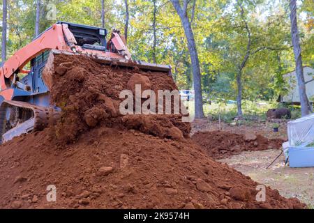 Ein kleiner Traktor, der für die Bodenbewegung für die Landschaftsgestaltung auf der Baustelle verwendet wird Stockfoto