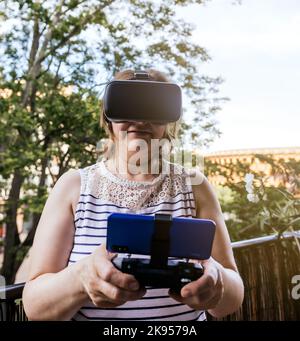 Eine Nahaufnahme einer Frau, die eine Virtual-Reality-Brille trägt und ein virtuelles Spiel spielt Stockfoto