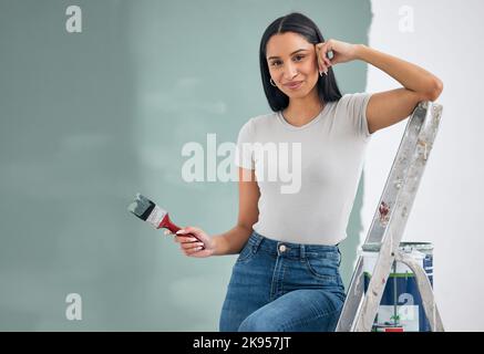 Wand, Porträt und Frau malen zu Hause mit einem Lächeln auf der Leiter für das Gleichgewicht mit mockup ruht. Renovierung, Verbesserung und junge Hausbesitzerin Mädchen Holding Stockfoto