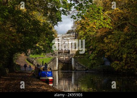 Ein Kahn (Schmalboot) ist an der Seite des Leeds Liverpool Kanals unter fünf Hochhausschleusen (Treppenschloss) in Bingley, West Yorkshire, vertäut. Stockfoto