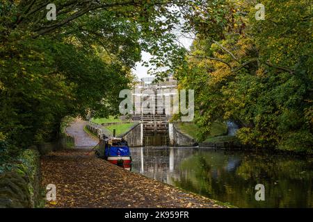 Ein Kahn (Schmalboot) ist an der Seite des Leeds Liverpool Kanals unter fünf Hochhausschleusen (Treppenschloss) in Bingley, West Yorkshire, vertäut. Stockfoto