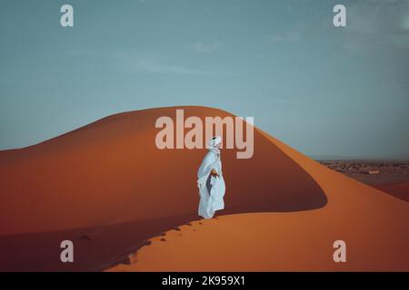 Ein Mann, der auf dem Wüstensand unter der Sonnenhitze steht Stockfoto