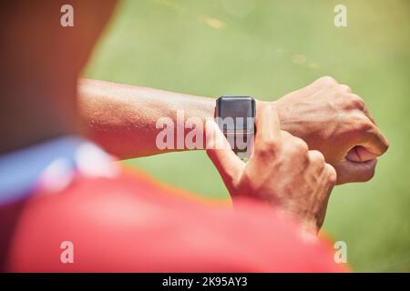 Smartwatch, Screen-Mock-Up und Fitness-Hands-Mann überprüfen die Laufergebnisse, den Fortschritt des Sport- oder Trainingsfortschritts auf dem grünen Spielfeld. Athlet on Stockfoto