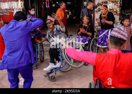 Kathmandu, Nepal. 26. Oktober 2022. Menschen mit Behinderungen und Beeinträchtigungen tanzen und singen zum Lied von Deusi Bhailo, das während des Tihar-Festivals, bekannt als Diwali, dem Lichterfest in Boudhanath Stupa, einem UNESCO-Weltkulturerbe in Kathmandu, für Glück, Freude und Glück unter den Menschen gesungen wird. Ein Team von dreizehn Menschen mit unterschiedlichen Behinderungen initiierte die 3-tägige musikalische Veranstaltung von Deusi Bhailo für das soziale Bewusstsein und die Bedeutung des großen Hindu-Festivals in der Gesellschaft mit Wünschen an alle Nepalesen auf der ganzen Welt. Kredit: SOPA Images Limited/Alamy Live Nachrichten Stockfoto