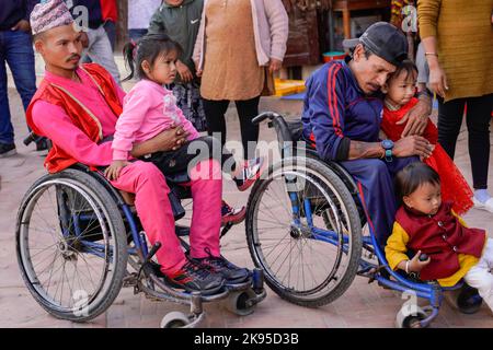 Kathmandu, Nepal. 26. Oktober 2022. Menschen mit Behinderungen und Beeinträchtigungen sitzen mit Kindern, deren Mütter ehrenamtlich sind, während sie tanzen und das Deusi-Bhailo-Lied singen, gesungen für Glück, Freude, Und das Glück unter den Menschen während des Tihar-Festivals, bekannt als Diwali, dem Lichterfest in Boudhanath Stupa, einem UNESCO-Weltkulturerbe in Kathmandu. Ein Team von dreizehn Menschen mit unterschiedlichen Behinderungen initiierte die 3-tägige musikalische Veranstaltung von Deusi Bhailo für das soziale Bewusstsein und die Bedeutung des großen Hindu-Festivals in der Gesellschaft mit Wünschen an alle Nepalesen auf der ganzen Welt. Stockfoto