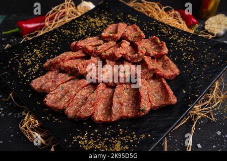 Rohes Hackfleisch auf schwarzem Steinteller. Geformtes Hackfleisch Stockfoto