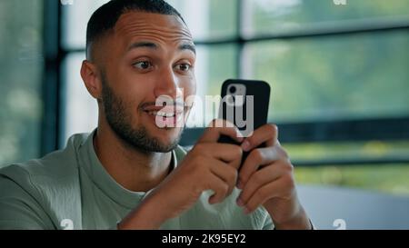 Nahaufnahme männlich Mann afrikanischer Geschäftsmann Kerl Unternehmer suchen Handy lesen Nachrichten E-Mail-Nachricht Angebot Ziel Leistung erstaunt Wunder schockiert Stockfoto
