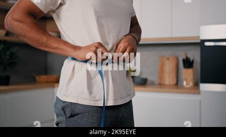 Unkenntlich sportlich männlich Sport Mann African guy misst Taille mit Maßband Check Gewichtsverlust Training Sport Diät gesund Stockfoto