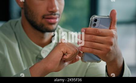 Nahaufnahme Halbgesicht afroamerikanischer bärtiger Mann in Innenräumen männlicher Kunde Geschäftsmann hält Smartphone im Heimbüro mit dem mobilen App-Service Stockfoto