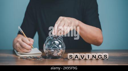 Familie finanzielle Sparplanung, man Hand hält Sparschwein auf Holztisch, Geld sparen Reichtum und Finanzkonzept, Geschäft, Finanzen, Investitionen Stockfoto