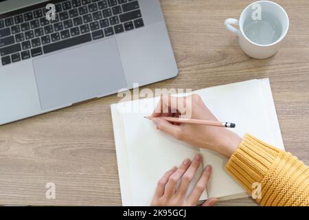 Eine Frau, die mit einem Bleistift Erinnerungen in ein Notizbuch schreibt Stockfoto