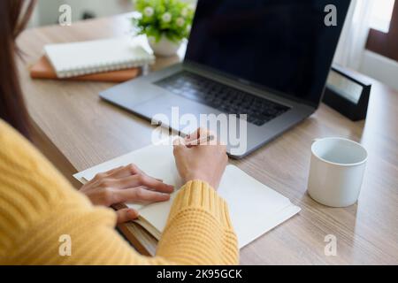 Eine Frau, die mit einem Bleistift Erinnerungen in ein Notizbuch schreibt Stockfoto