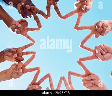 Friedenssternzeichen, Menschen und Hände von Menschen zusammen mit Vielfalt, die Unterstützung und Gemeinschaft zeigt. Unten Blick auf Freunde im Freien und blauen Himmel Stockfoto