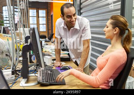 Die Medienagentur: Office Chat. Kreative Medienkollegen diskutieren über ein Projekt in einer modernen Open-Office-Umgebung. Aus einer Reihe verwandter Bilder. Stockfoto