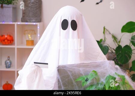 Ghost of Halloween nutzt Laptop im Internet surfen, Online-Shops durchsuchen, Märkte. Ein Geist macht eine Bestellung vom Computer für Halloween. Ghost zahlt für den Online-Kauf per Kreditkarte. Stockfoto