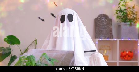 Ghost of Halloween nutzt Laptop im Internet surfen, Online-Shops durchsuchen, Märkte. Ein Geist macht eine Bestellung vom Computer für Halloween. Ghost zahlt für den Online-Kauf per Kreditkarte. Stockfoto