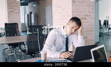 Ein erschöpfter depressiver Mann sitzt im Büro Stockfoto