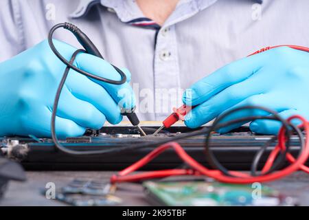 Hands Fixing Motherboard von pc oder Laptop Notebook Nahaufnahme in Betrieb. Reparatur von Laptops. Stockfoto