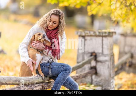 Eine gut aussehende junge Frau sitzt mit ihren Hunden im Park. Stockfoto