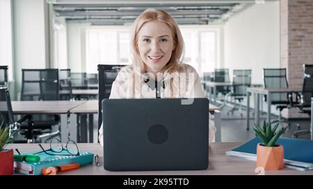 Eine junge Geschäftsfrau, die im Büro an ihrem Schreibtisch sitzt Stockfoto