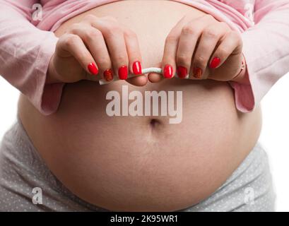 Nahaufnahme einer Schwangeren, die eine Zigarette bricht, isoliert auf weißem Hintergrund als Konzept der schlechten Gewohnheit Stockfoto