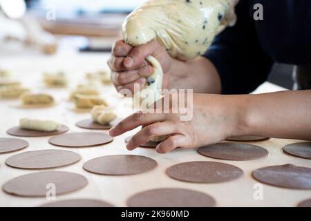 Frau bereitet frisch zubereitete Ravioli in der Pasta-Fabrik zu. Mit einem Tütchen oder einem Beutel einen Poche gefüllte Pasta Ravioli, Culurgiones, agnolotti zu machen. Fokus Stockfoto