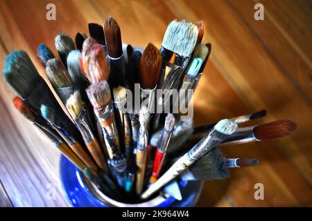 Eine Nahaufnahme der Pinsel des Künstlers in der blauen Vase. Stockfoto