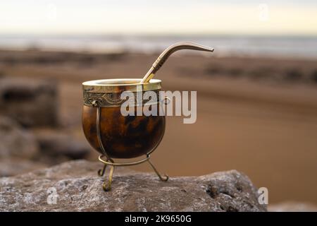 Eine Nahaufnahme eines argentinischen Mate-Pokals in goldenen und braunen Farben auf einem isolierten Hintergrund Stockfoto
