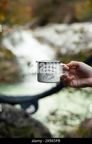 Eine Tasse mit kreativem Motivationszitat vor herbstlichem Hintergrund (Sonne oder Schnee in den Bergen gehen wir). Das Konzept von Reisen und Abenteuern Stockfoto