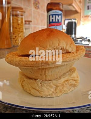 Wigan Lancashire Pie Burger, Steak- oder Fleischpastete auf einem Muffin mit Ofenboden, mit HP Sauce Bottle – nordwestlich des britischen Komfortgerichts, Großbritannien Stockfoto