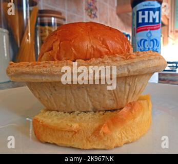Wigan Lancashire Pie Burger, ein Steak- oder Fleischkuchen auf einem Muffin im Ofen, mit HP-Saucenflasche Stockfoto