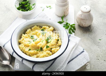 Kartoffelpüree. Heiße Kartoffelpüree mit Butter, frischen Petersilienkräutern und Pfeffer in einer Schüssel auf Schiefer-, Stein- oder Betonböden. Köstliche cremige Mas Stockfoto